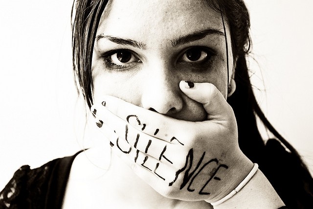 women holding her mouth with silence written on her hand